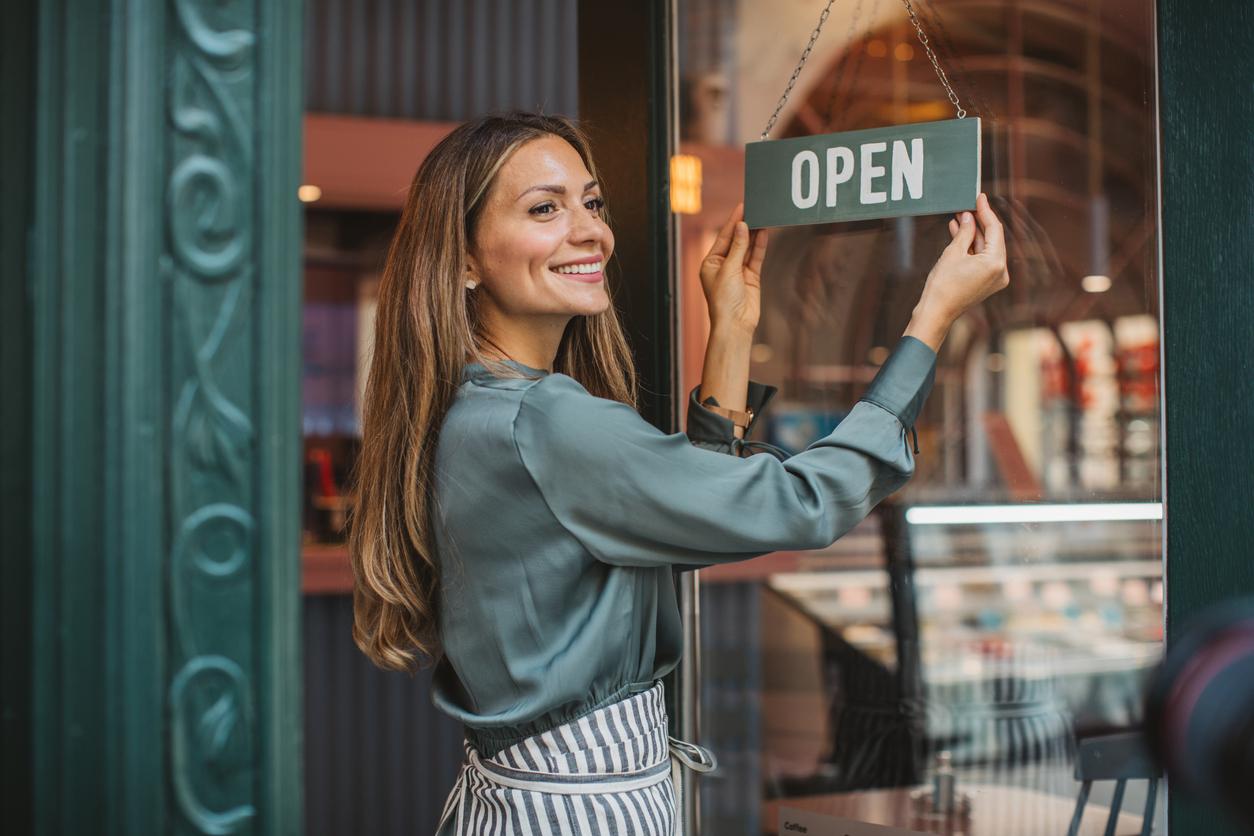 vrolijke vrouw die winkel opendoet